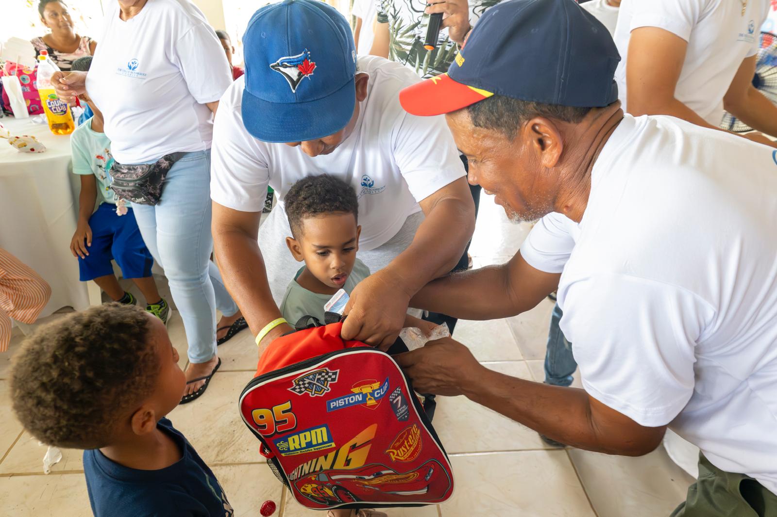 Volunteers distributing backpacks to children at VelRod event