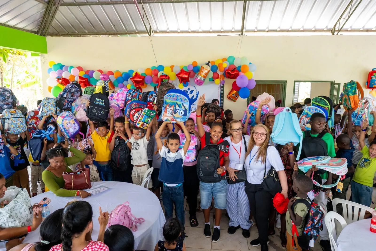 Children holding up their new backpacks at the 2026 Back-to-School Drive